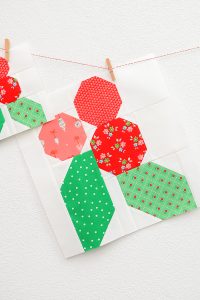 12 Inch Holly Berry quilt block hanging on a wall